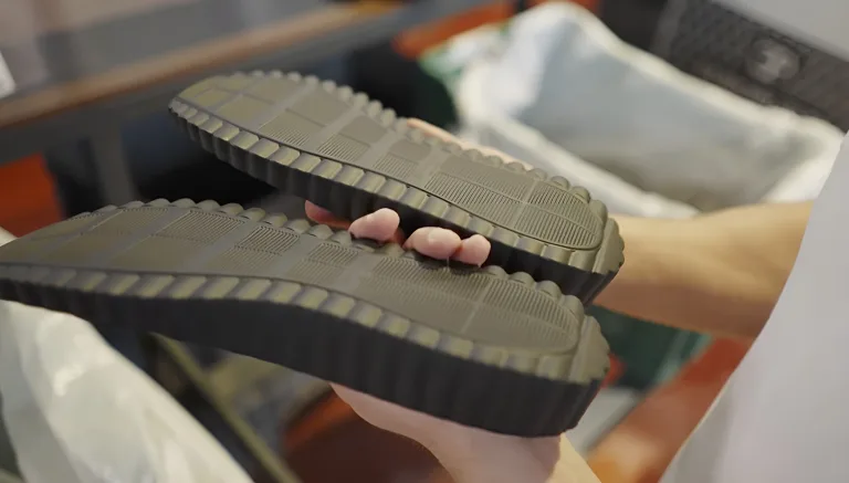 Hands holding two dark grey soles